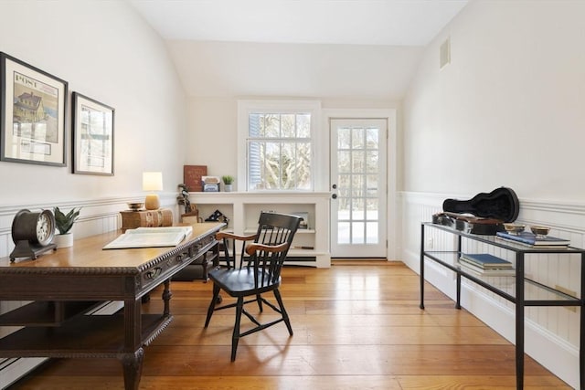 office featuring wainscoting, vaulted ceiling, hardwood / wood-style floors, and visible vents