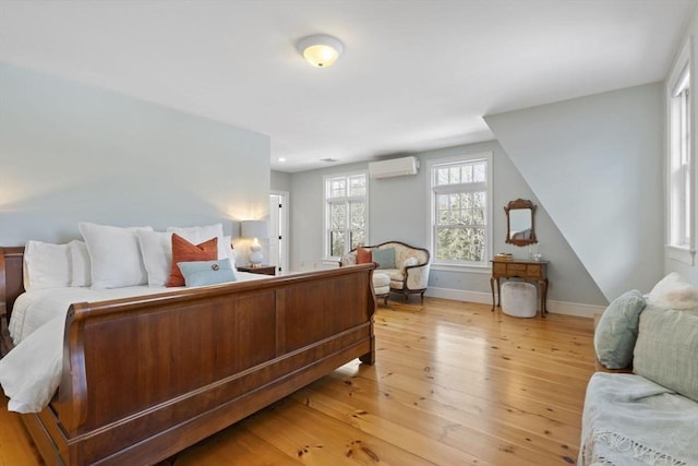 bedroom featuring light wood-style floors, a wall mounted air conditioner, and baseboards