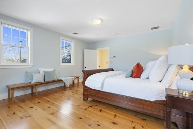 bedroom featuring baseboards, light wood finished floors, and visible vents