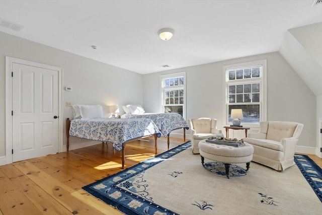 bedroom with wood-type flooring, baseboards, visible vents, and lofted ceiling