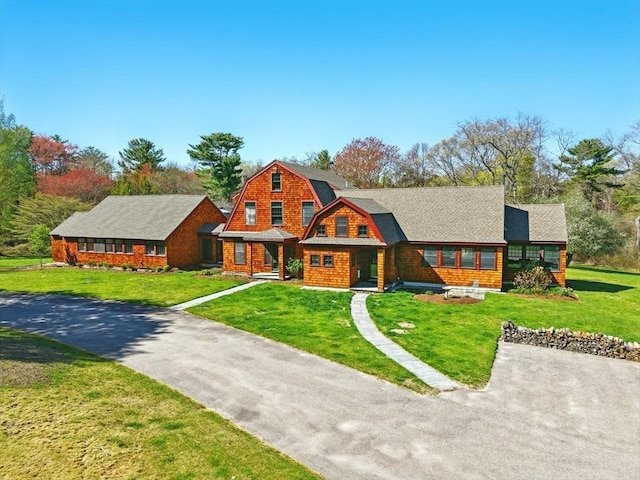 view of front facade with a front lawn and a gambrel roof