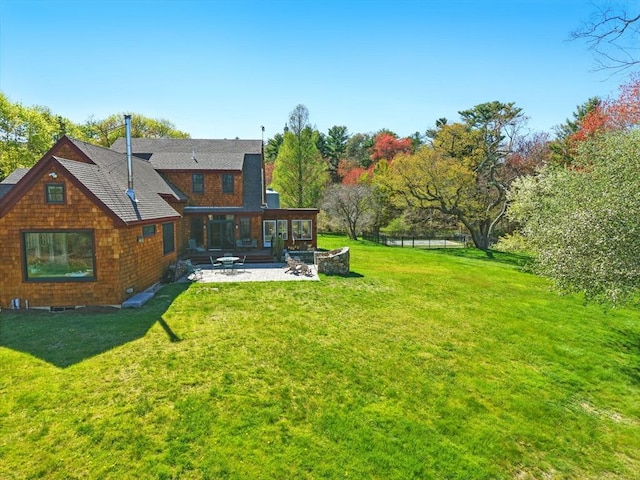 rear view of property with fence, a shingled roof, a yard, and a patio area