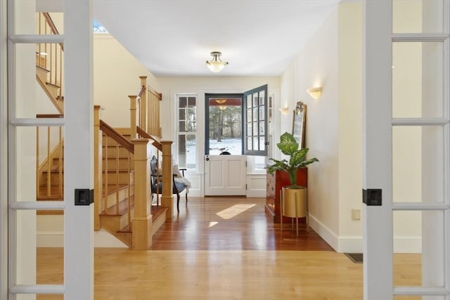 entryway featuring stairs, baseboards, and wood finished floors