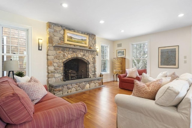 living room with recessed lighting, light wood-style floors, baseboards, and a fireplace