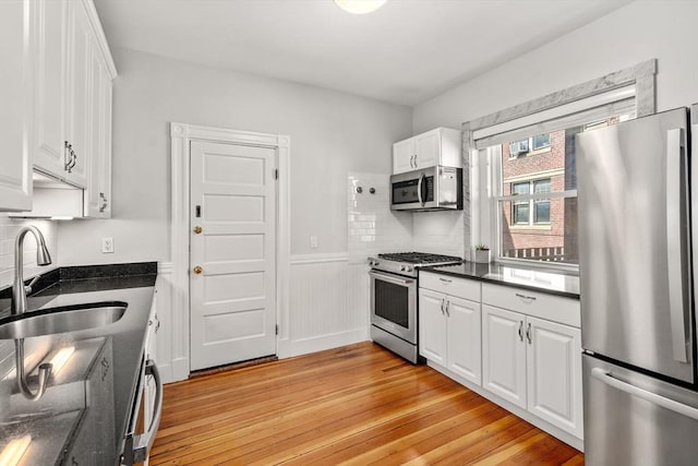 17 Park Vale Unit 2, Brookline, MA 02446 - kitchen with appliances with stainless steel finishes, a sink, light wood-style flooring, white cabinetry, and wainscoting