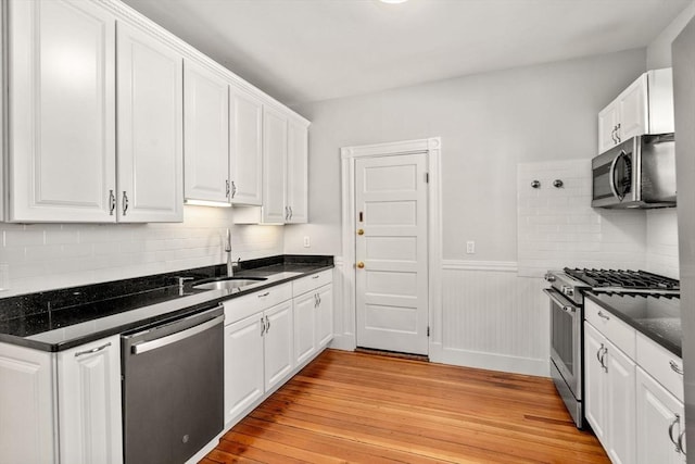 17 Park Vale Unit 2, Brookline, MA 02446 - kitchen with stainless steel appliances, a sink, light wood-type flooring, white cabinetry, and a wainscoted wall