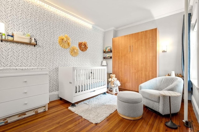 17 Park Vale Unit 2, Brookline, MA 02446 - bedroom with wallpapered walls, ornamental molding, wood finished floors, a crib, and baseboards