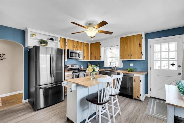 kitchen featuring open shelves, light wood-style flooring, a sink, stainless steel appliances, and butcher block counters