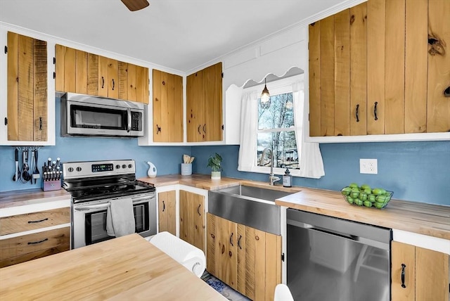 kitchen with a sink, stainless steel appliances, wooden counters, and crown molding