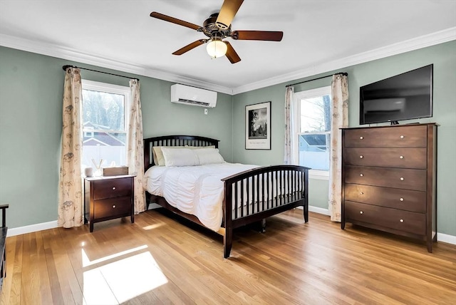 bedroom with a wall unit AC, light wood-style floors, baseboards, and ornamental molding