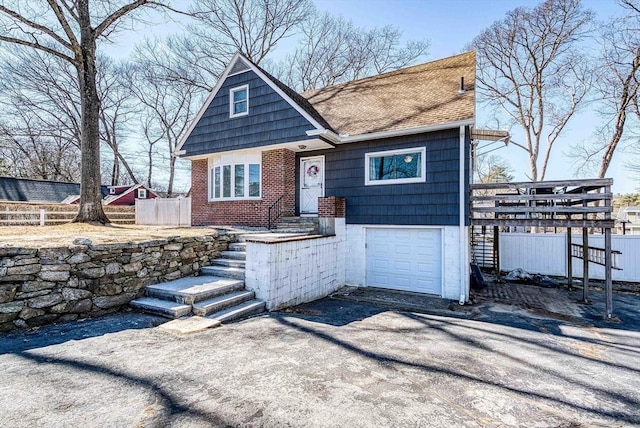 view of front of house featuring fence, a shingled roof, a garage, aphalt driveway, and brick siding