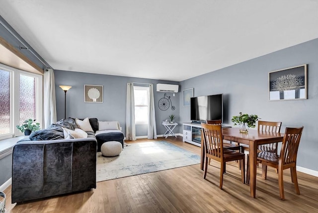 living room with a wall mounted air conditioner, baseboards, and wood finished floors