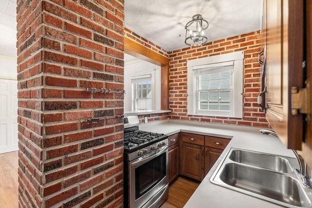 67-69 Nesmith St, Lawrence, MA 01841 - kitchen with stainless steel gas range, wood finished floors, light countertops, brick wall, and a chandelier