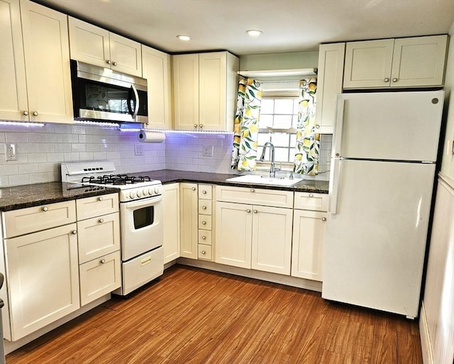 kitchen featuring wood-type flooring, sink, white cabinets, and white appliances