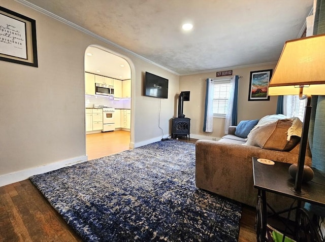 living room with crown molding, a wood stove, and hardwood / wood-style floors