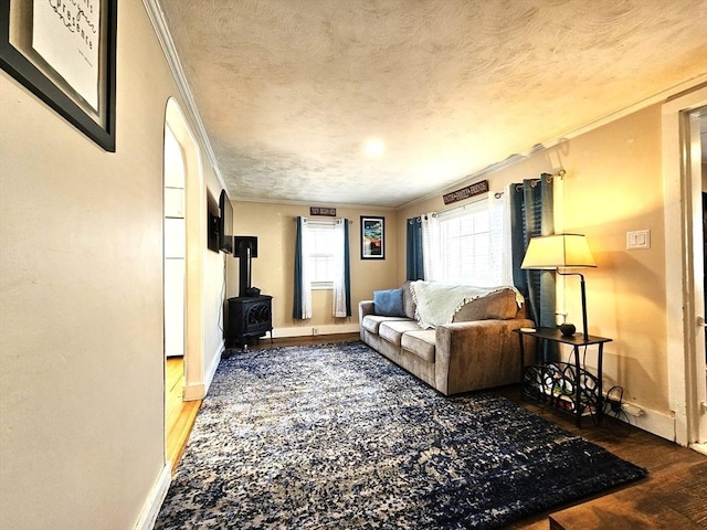 living room featuring hardwood / wood-style flooring, crown molding, a textured ceiling, and a wood stove