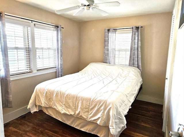 bedroom with ceiling fan, dark hardwood / wood-style flooring, and multiple windows