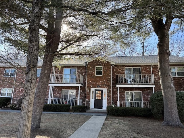 multi unit property with brick siding, a porch, and a balcony