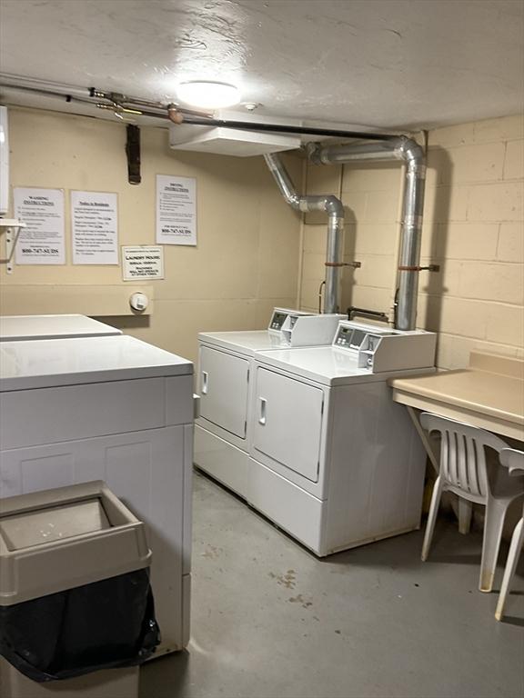 shared laundry area featuring washing machine and clothes dryer and concrete block wall