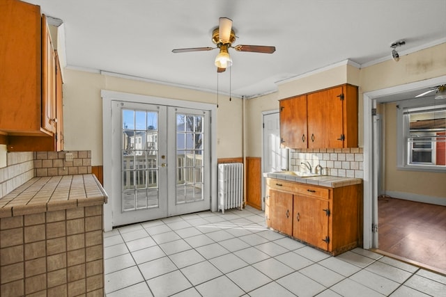 kitchen featuring tile countertops, light tile patterned flooring, ornamental molding, and french doors