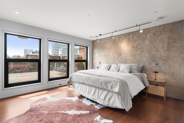 bedroom featuring wood finished floors and rail lighting