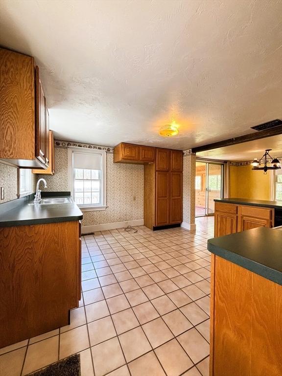 45 Gardner Rd, Hubbardston, MA 01452 - kitchen with a sink, dark countertops, light tile patterned flooring, brown cabinets, and wallpapered walls