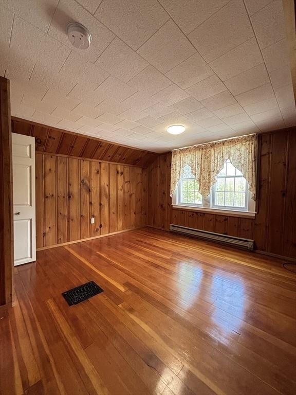45 Gardner Rd, Hubbardston, MA 01452 - spare room with a baseboard heating unit, hardwood / wood-style flooring, wooden walls, baseboards, and a smoke detector