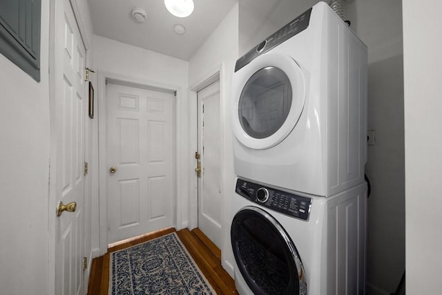 laundry area featuring dark wood-style floors, laundry area, and stacked washing maching and dryer