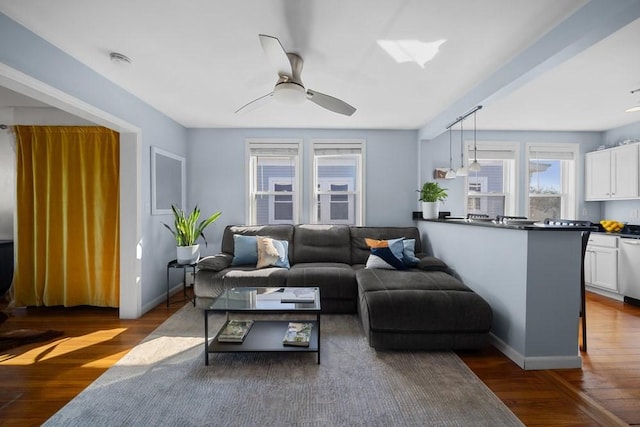 living room with dark wood finished floors, a ceiling fan, and baseboards