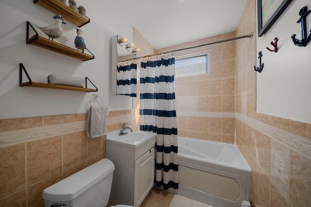 full bath with tile walls, toilet, shower / bath combo with shower curtain, wainscoting, and vanity