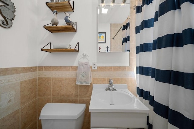 bathroom with toilet, curtained shower, tile walls, and vanity