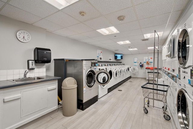 shared laundry with stacked washer / drying machine, light wood finished floors, and washing machine and clothes dryer