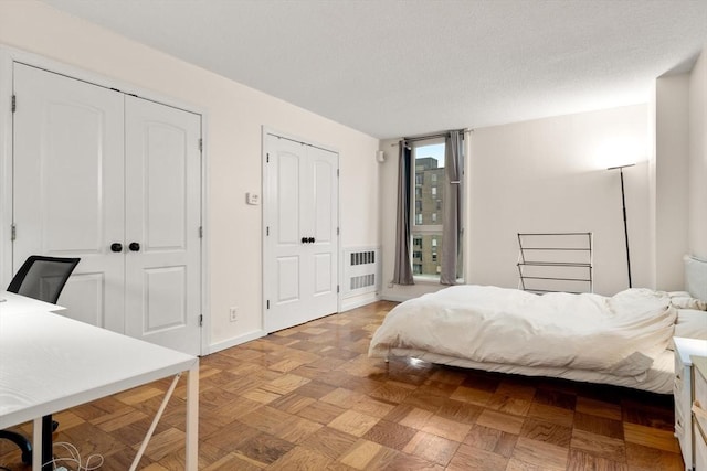 bedroom featuring radiator heating unit, two closets, and baseboards