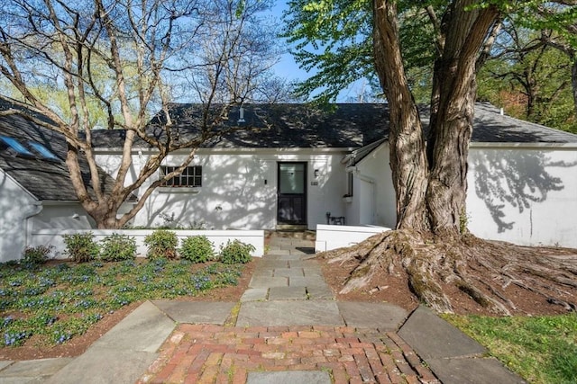 view of front of property featuring a shingled roof and stucco siding