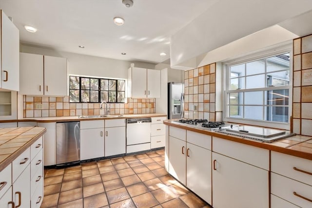 kitchen with stainless steel fridge, a sink, a healthy amount of sunlight, and dishwasher
