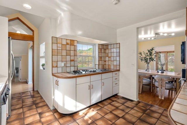 kitchen with white cabinets, tile counters, baseboards, stainless steel gas stovetop, and tasteful backsplash