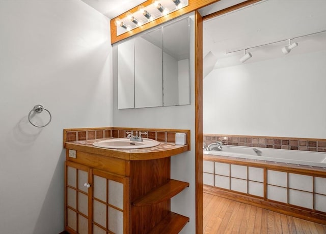 bathroom featuring vanity, wood-type flooring, and a bath