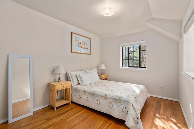 bedroom with baseboards, light wood-style flooring, and vaulted ceiling