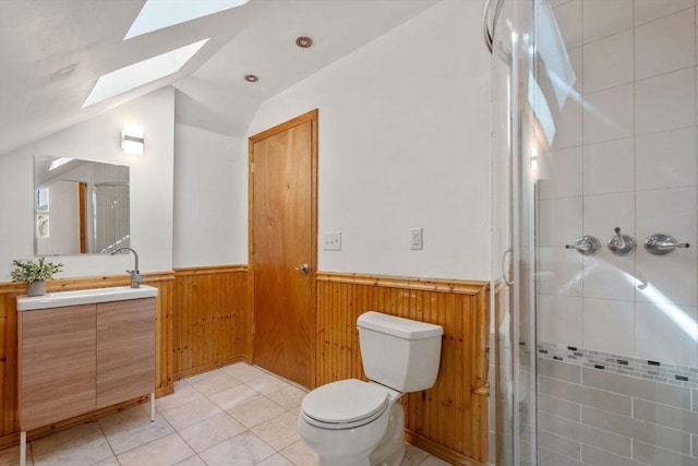 bathroom with vanity, wainscoting, a stall shower, and lofted ceiling with skylight