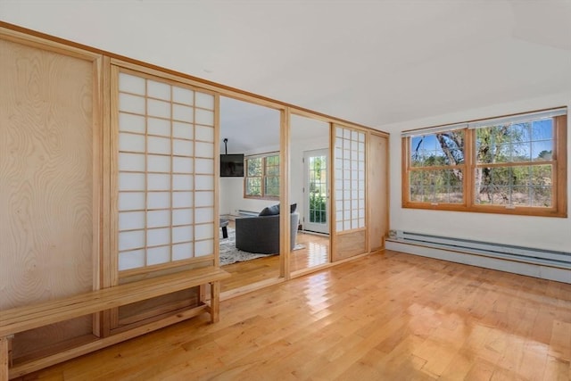 unfurnished living room with light wood-style floors and a baseboard heating unit