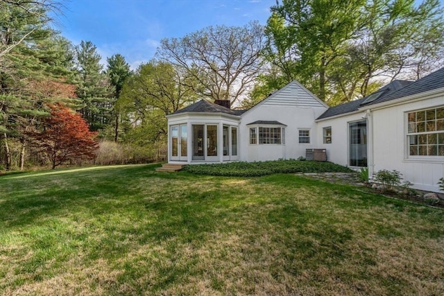rear view of house featuring a lawn, cooling unit, and a chimney
