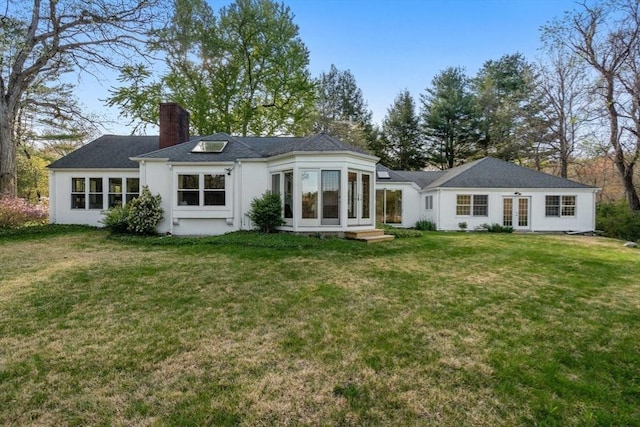 back of house with stucco siding, french doors, a chimney, entry steps, and a yard