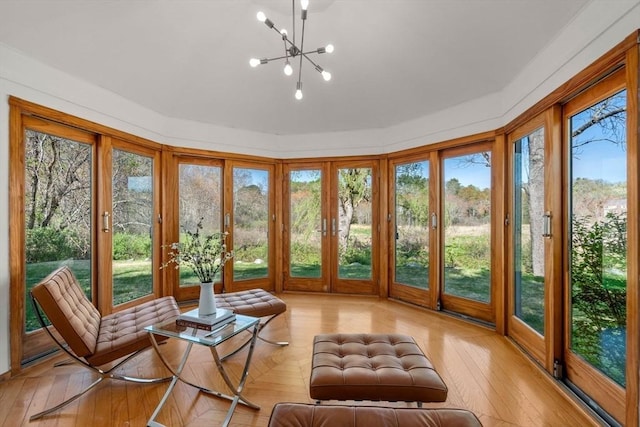 sunroom with a chandelier, a healthy amount of sunlight, french doors, and hardwood / wood-style flooring