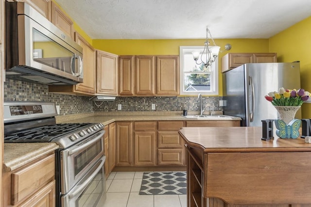 kitchen featuring light tile patterned flooring, a notable chandelier, a sink, stainless steel appliances, and backsplash