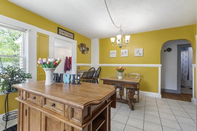 dining space featuring arched walkways, baseboards, an inviting chandelier, and light tile patterned flooring