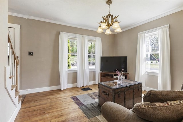 living area with light wood-style floors, ornamental molding, a chandelier, and stairway