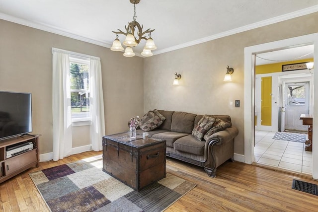 living room with crown molding, baseboards, an inviting chandelier, and light wood-style floors