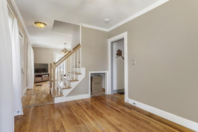 interior space with wood finished floors, stairway, baseboards, a chandelier, and ornamental molding