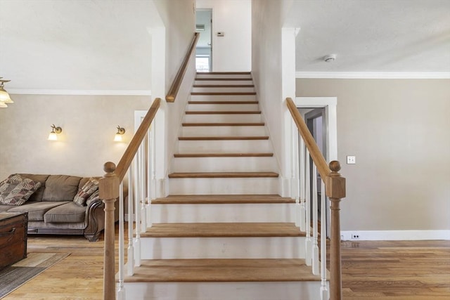 stairs with crown molding, baseboards, and wood finished floors