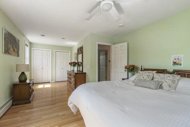 bedroom featuring multiple closets, baseboards, ceiling fan, light wood-type flooring, and a baseboard heating unit